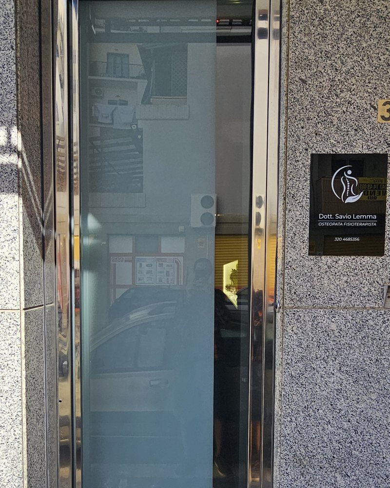 L'ingresso dello studio visto dalla strada: la porta a vetri e, accanto, la targa Dott. Savio Lemma, osteopata fisioterapista